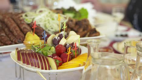 fresh fruit platter on festive dinner table. assorted sliced fruit skewers