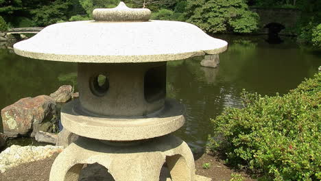 a japanese "snow gazing lantern" stands in front of a pond