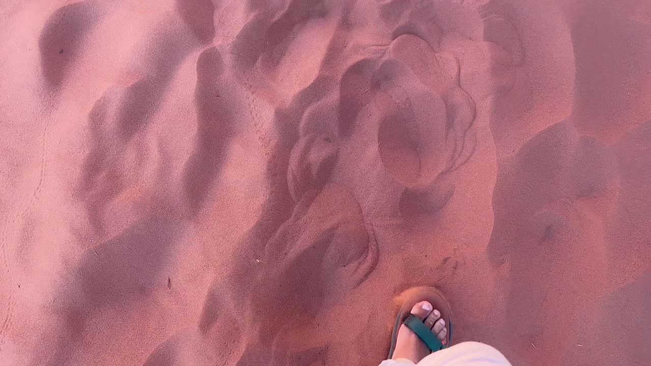 Walking on red sand with sandals on in the red desert of Wadi Rum in Jordan