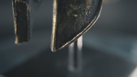 a close up macro spiral slow tilt up shot of a spartan face design, warrior ancient greek bronze helmet, on a 360 rotating stand, studio lighting, 4k smooth movement