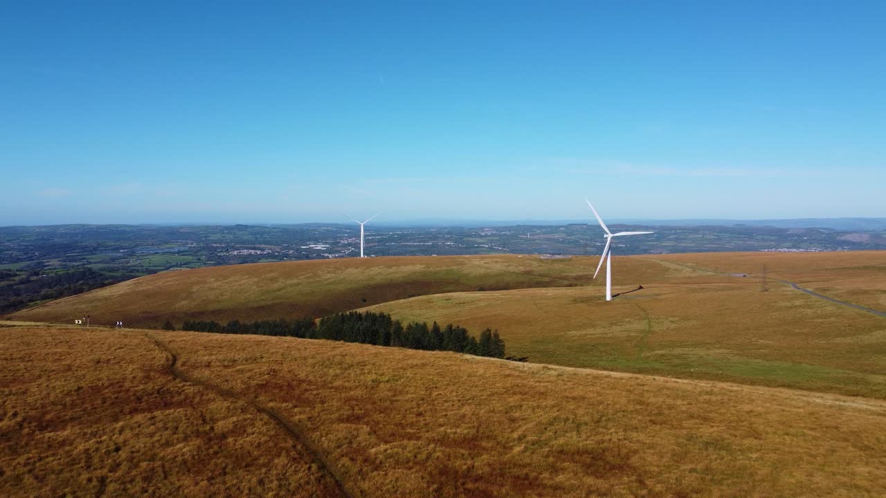 Pushing Aerial on Wales Countryside with Wind Turbine Farm and Pine Tree Forest Plantation. Renewable Energy Environmental Footage 4K