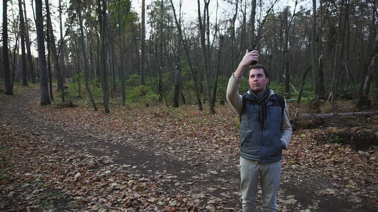 hombre tomando una selfie en un bosque de otoño