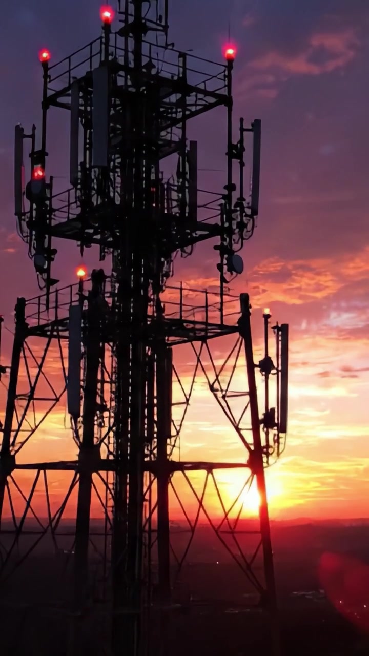 Una silhouette mozzafiato al tramonto dietro una torre di telecomunicazioni, che mostra colori vivaci nel cielo mentre il giorno si trasforma in notte.