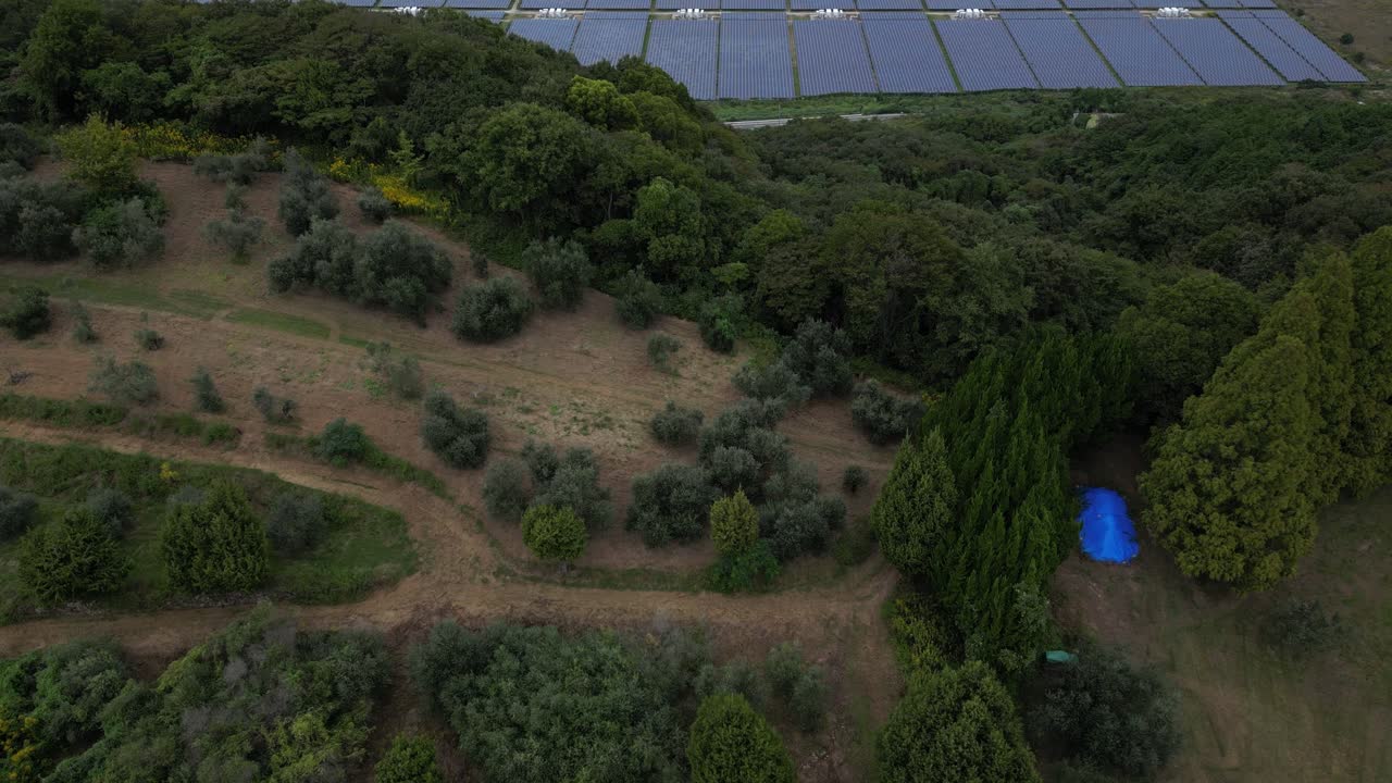 Slow motion drone tilt up reveal over solar farm in rural Japan