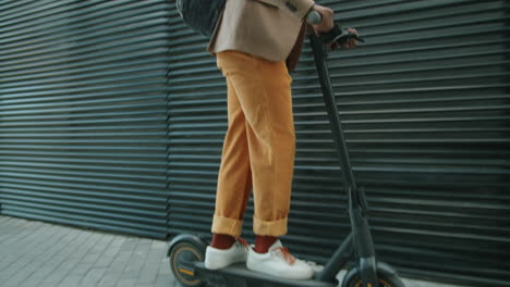 hombre afroamericano montando un scooter eléctrico en la ciudad