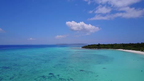 carretilla aérea hacia adelante sobre aguas azules poco profundas y barco en las islas del paraíso de maldivas 4k