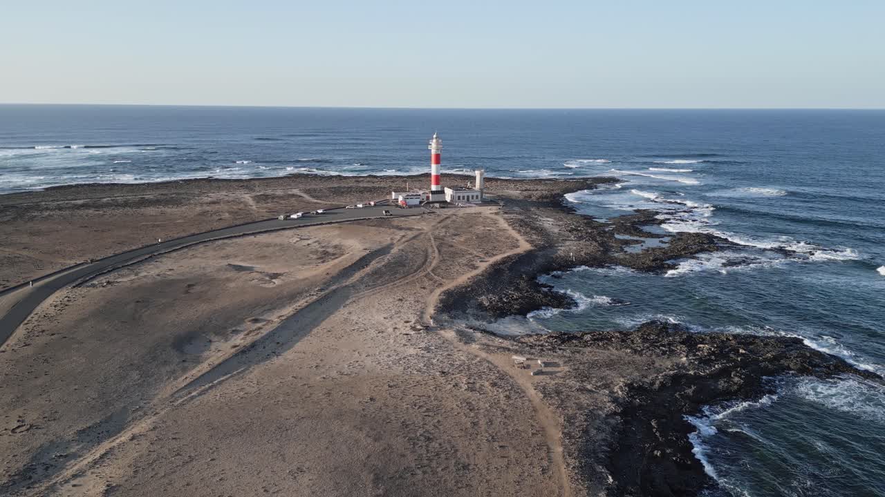 Drone footage of El Tostón Lighthouse in El Cotillo, Fuerteventura, during sunset — golden light over volcanic coastline and Atlantic waves.