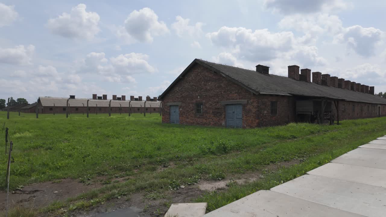 Exterior view of Auschwitz-Birkenau, vast fields and barbed wire, reflecting Holocaust horrors