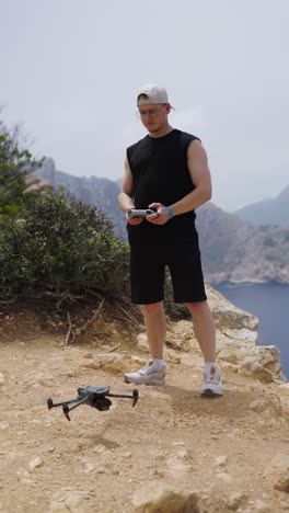 vertical shot of male drone pilot perform take off maneuver from cliff