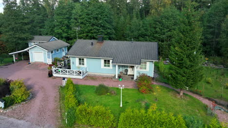 drone shot circling a wooden house in middle of forest, autumn day in finland
