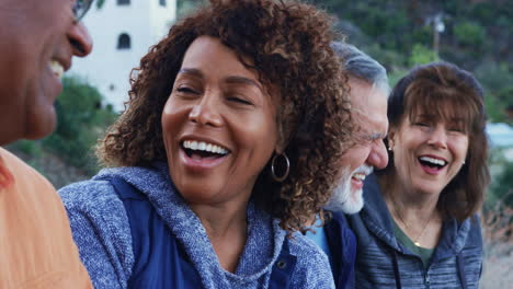 group of senior friends on hike in countryside talking and laughing together