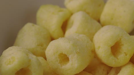cerca de los bocadillos de comida crujiente anillos de maíz patatas saladas gira lentamente. comida rápida o comida chatarra bocadillos concepto no saludable.