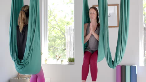 diverse fitness teenage girls in aerial yoga class with female coach in big white room, slow motion