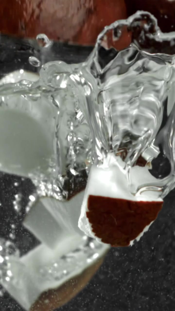 Movimento rallentato di pezzi di cocco che cadono in acqua cristallina con schizzi