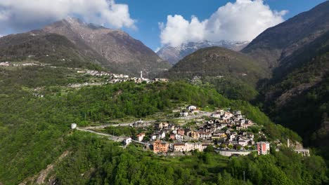 drone crane motion toward picturesque alp village in lush hillside forest