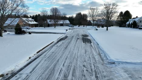 drone flies along icy snow covered street in usa toward cul de sac dead end