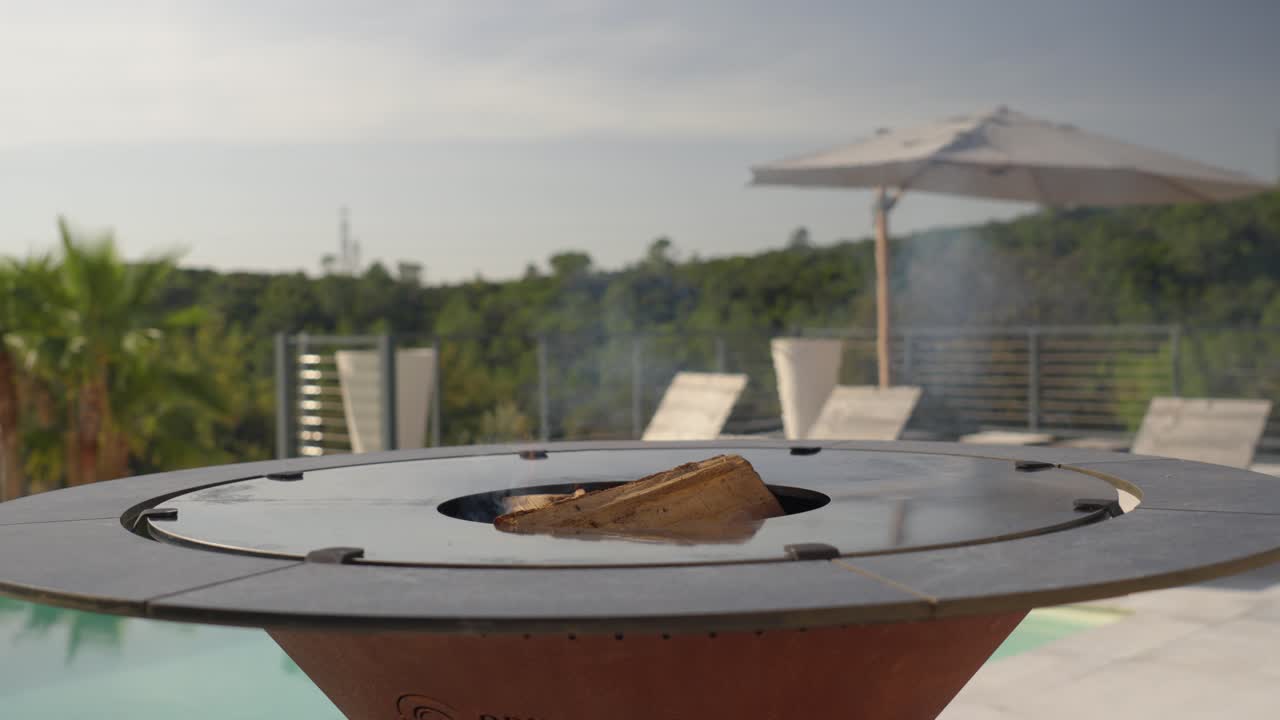 orbiting a fireplace burning fire logs on a rooftop balcony during summer