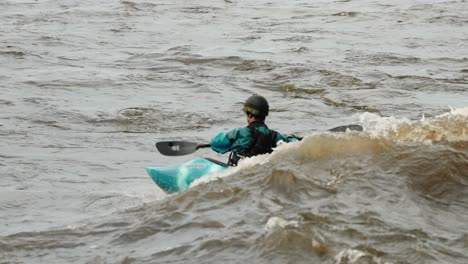 kayaker surfs the wake of a wave generated by the flood water rapids of the ottawa river