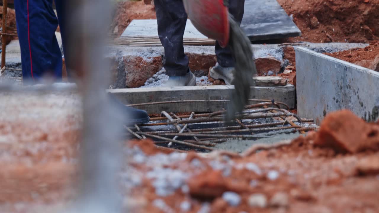 Concrete Pouring on steel reinforcement bars with red soil at construction site. day time, stable shot, low angle shot, 4k