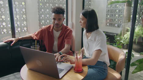 man and woman using laptop while coworking in cafe