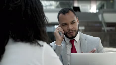 thoughtful young businessman talking on smartphone