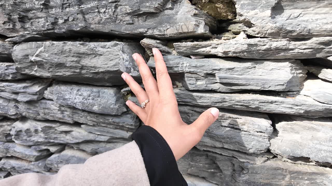 A hand touching a textured stone wall