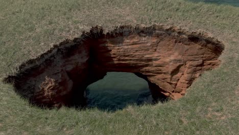 agua ondulante del río san lorenzo vista desde el agujero de la cueva en el suelo de las islas magdalen con hierba verde en un día soleado en quebec, canadá