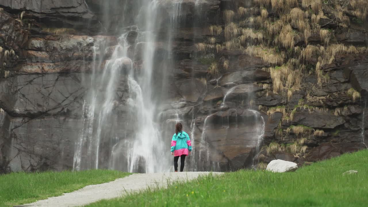 Girl admiring a majestic waterfall in Norway
