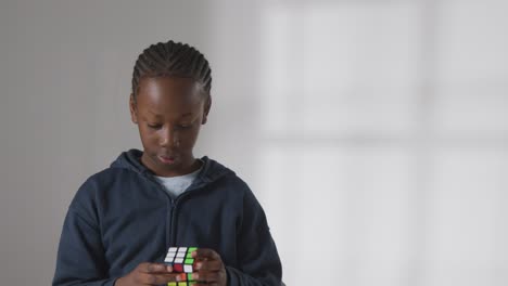 studio shot of boy on asd spectrum solving puzzle cube on white background