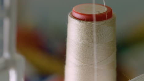 CLOSE-UP-spool-of-a-running-sewing-machine,-thread-unwinding