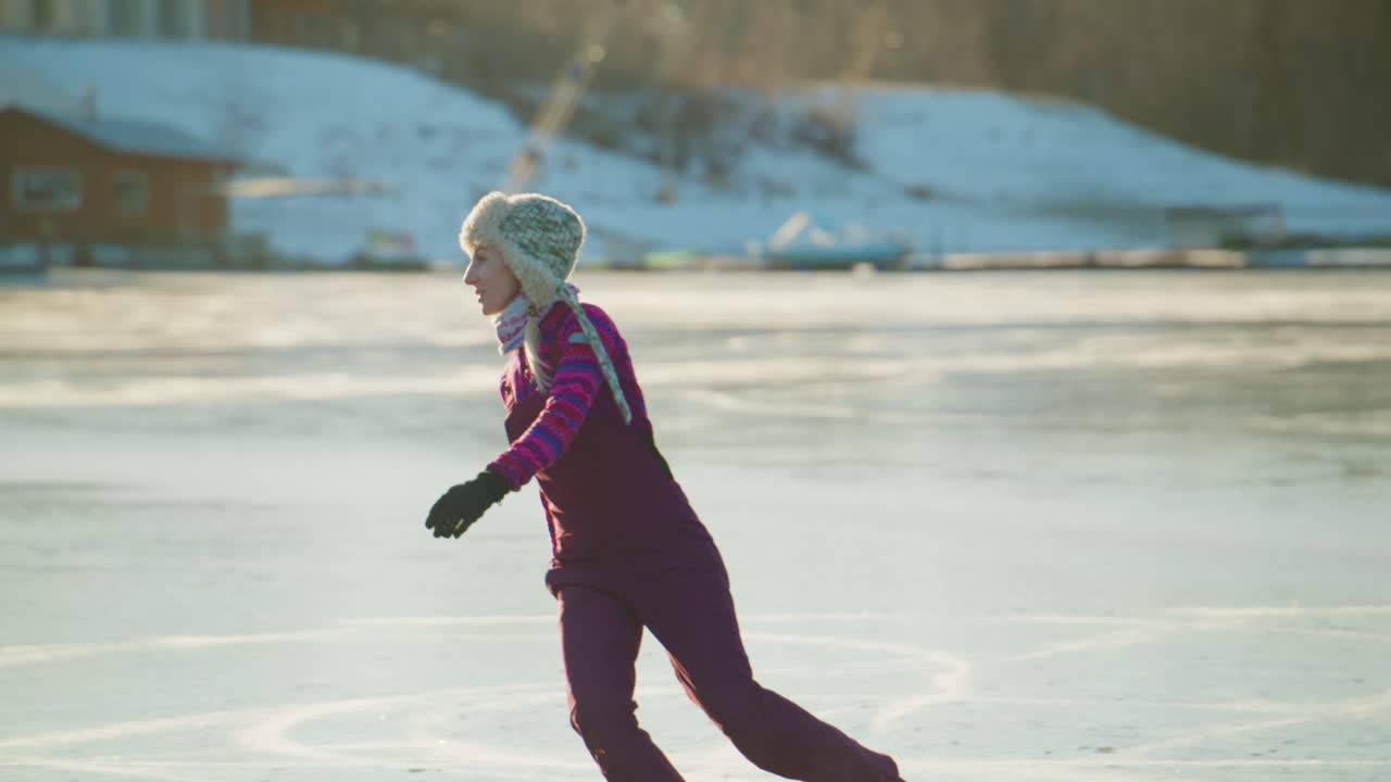 En glad, ung pige står elegant på skøjter på en frossen sø og viser sine evner frem, omgivet af et malerisk vinterlandskab, der understreger skøjteløbets skønhed som en sjov aktivitet i naturen.