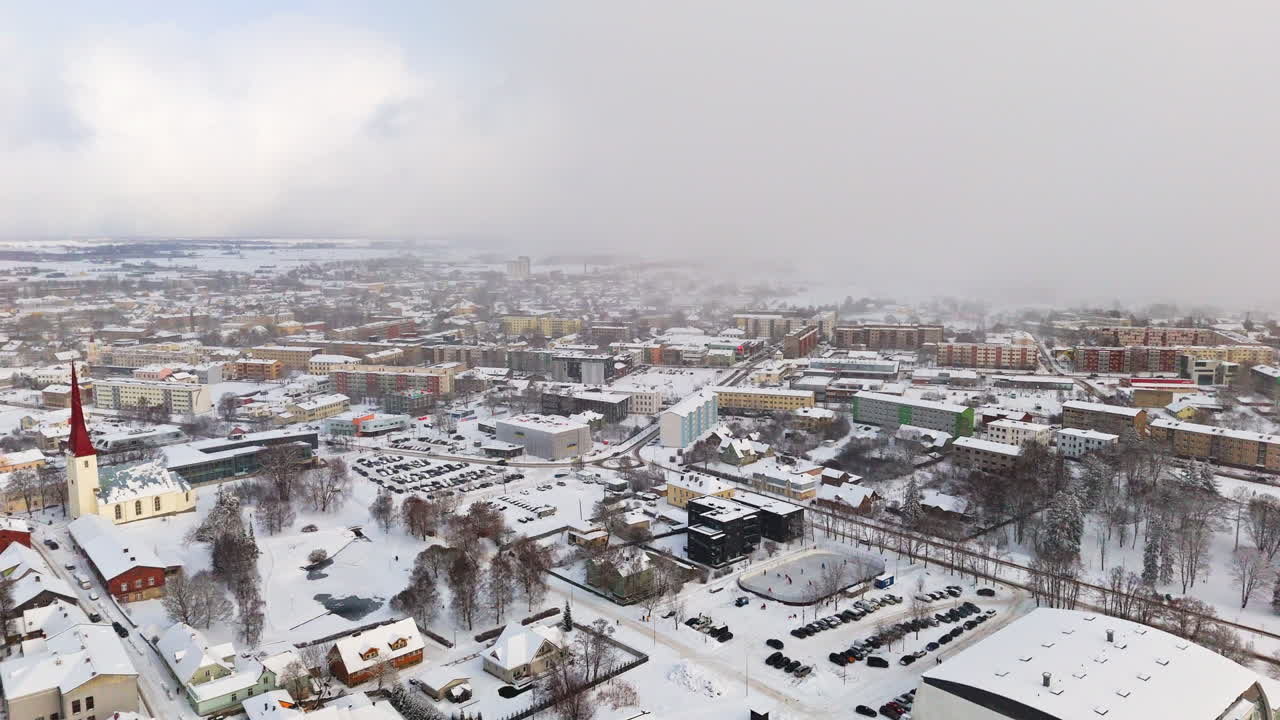 Establishing drone shot of the snowy cityscape, snowstorm in Rakvere, Estonia