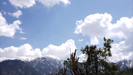 el lapso de tiempo de las montañas cubiertas de nieve con nubes esponjosas por encima disolviéndose en el cielo