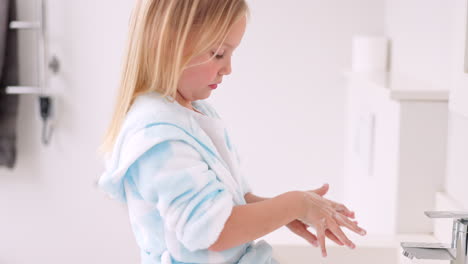 child washing hands in bathroom