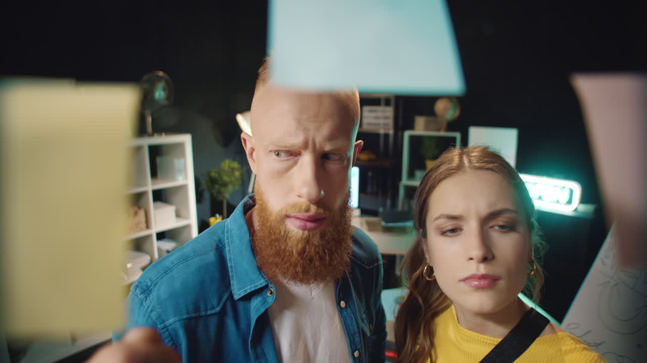 удивленный хипстер и женщина нашли хорошую идею на прозрачной стене в офисе.