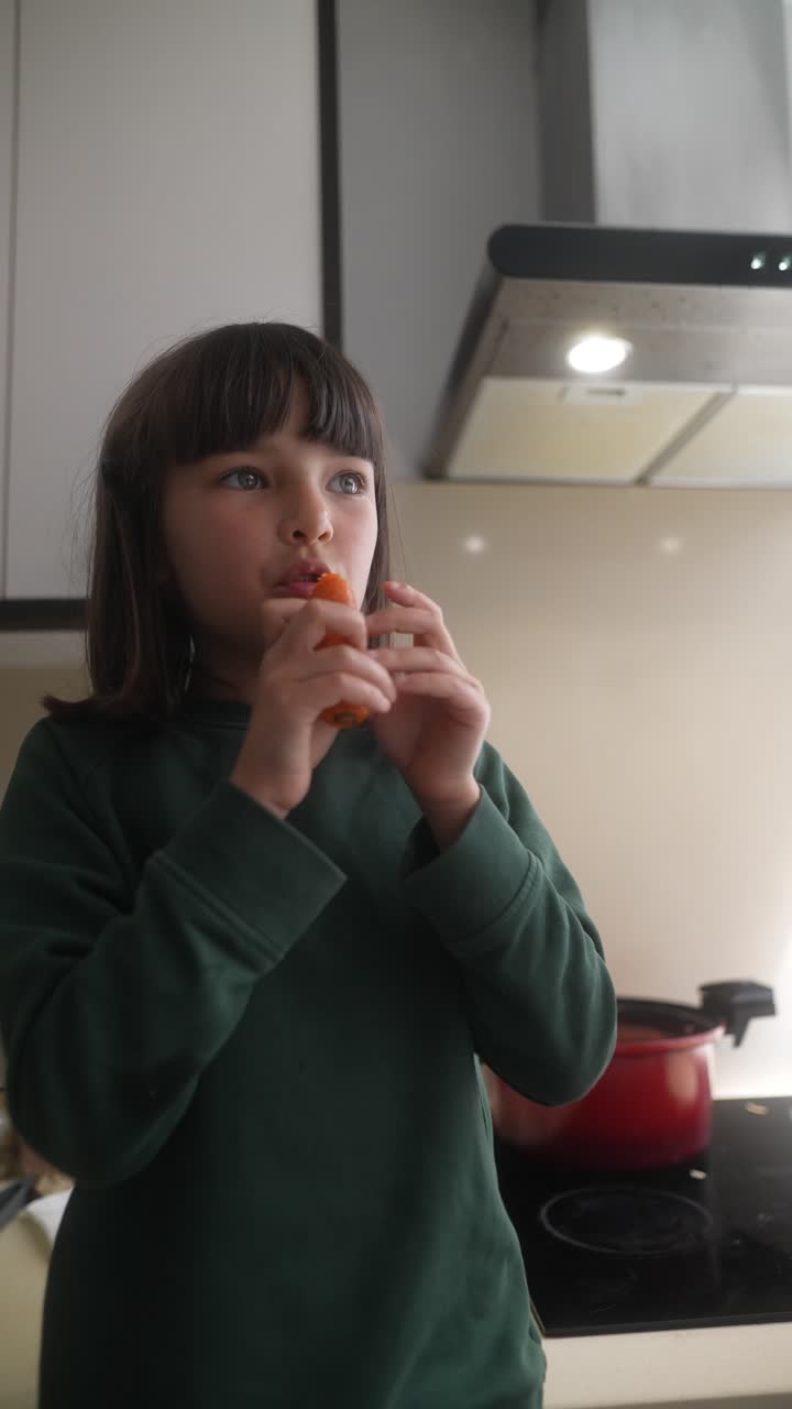 Girl eating a carrot in the kitchen