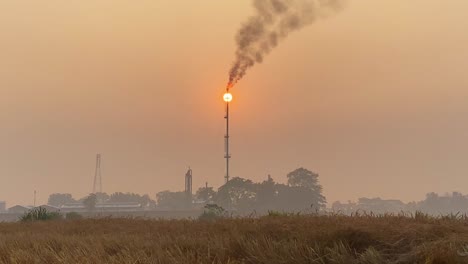 Telephoto-closeup-of-Gas-Plant-flame-matching-sun,-hazy-orange-sky,-static