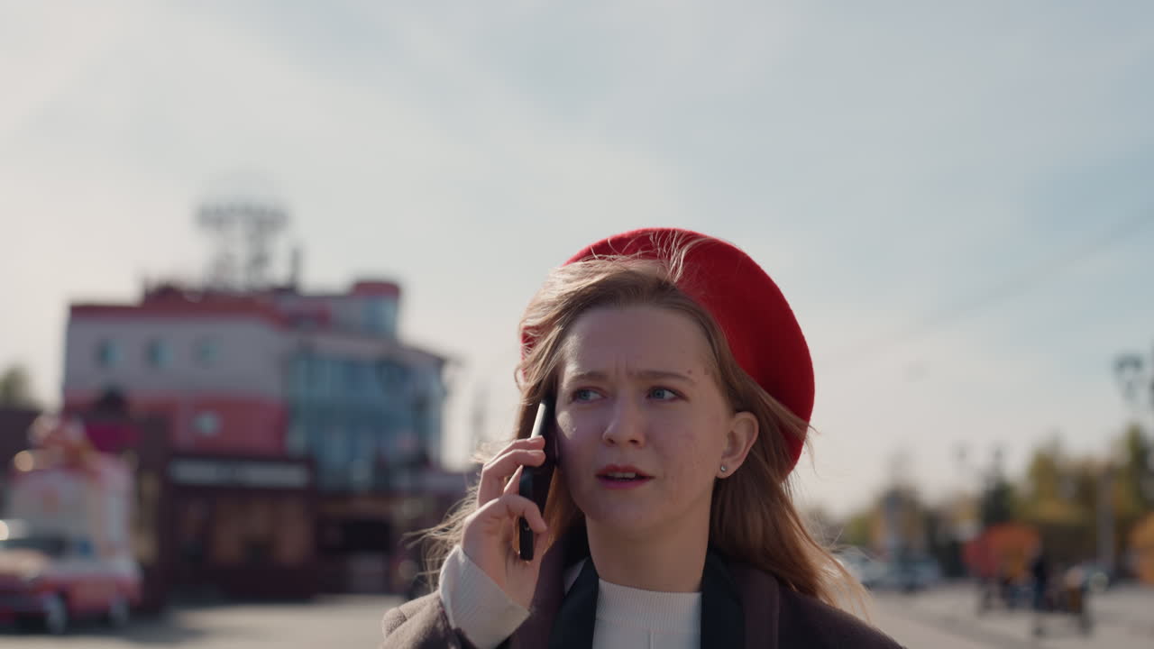 Bykvinde svarer. Ængstelig urban kvinde viser anspændt reaktion under gadeopkald. Byboende kvinde reagerer med mærkbar angst, mens hun svarer på et presserende telefonopkald på travl gade.