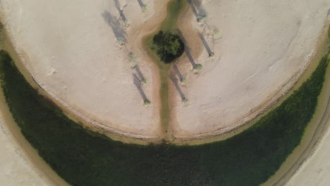 Drone-view-of-the-Moon-Lake-in-Dubai,-Moon-Shape-Lake-is-in-the-middle-of-Al-Qudra-desert,-surrounded-by-golden-sand-dunes-in-the-United-Arab-Emirates