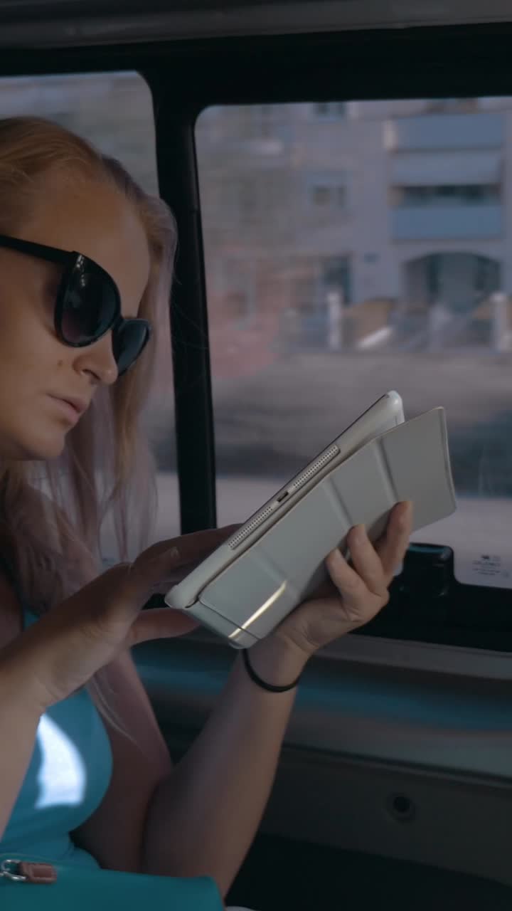 Giovane donna che usa il tablet mentre viaggia in auto