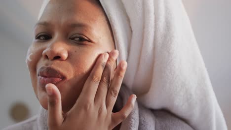 Happy-african-american-plus-size-woman-applying-face-cream,-unaltered,-slow-motion