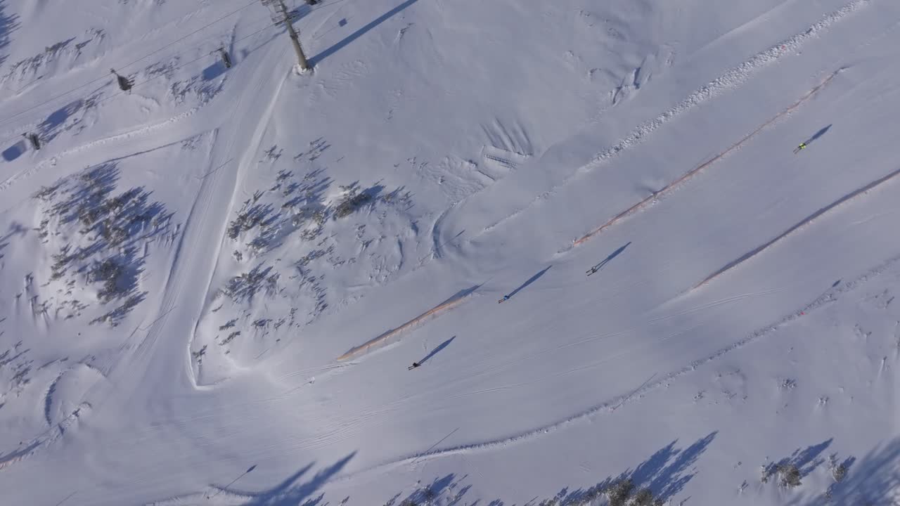 Skiløbere, der svinger ned ad pisterne under en travl skilift på Obertauern resort, Østrig