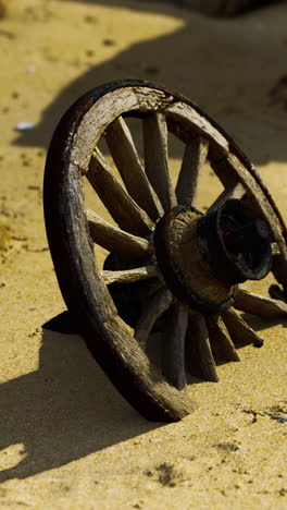 closeup of an old wooden wheel on a sandy beach