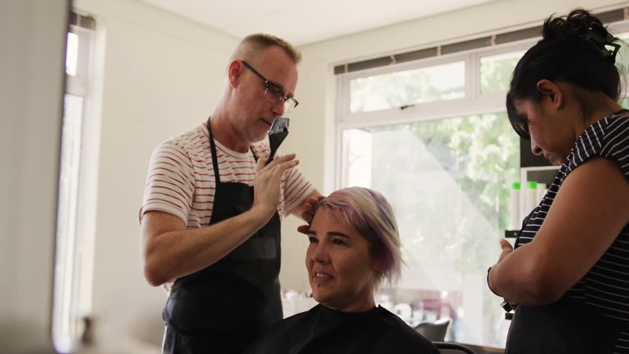 Zijaanzicht van een vrouw die haar haar laat stylen door twee kappers