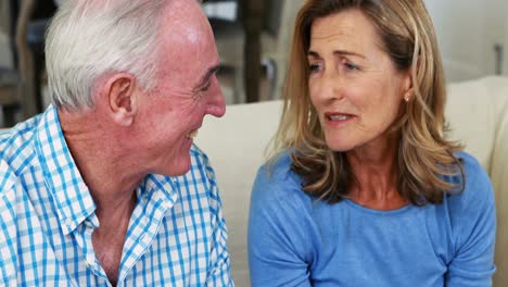 Smiling-senior-couple-interacting-with-each-other-while-having-cup-of-coffee-in-living-room