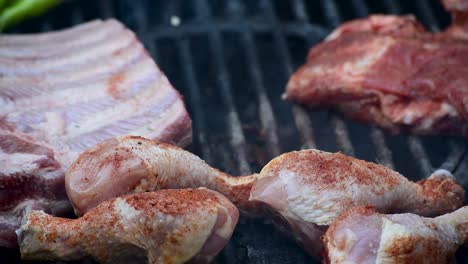 ribs and spice rubbed chicken legs on outdoor grill closeup showing flames and smoke with copy space