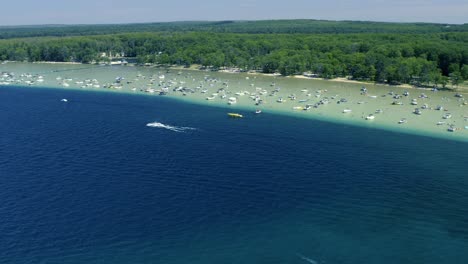 Toma-Aérea-De-Botes-En-Un-Lago-Glacial-Claro-En-Verano-Con-Una-Bajada-Distinta-De-Aguas-Poco-Profundas-A-Profundas