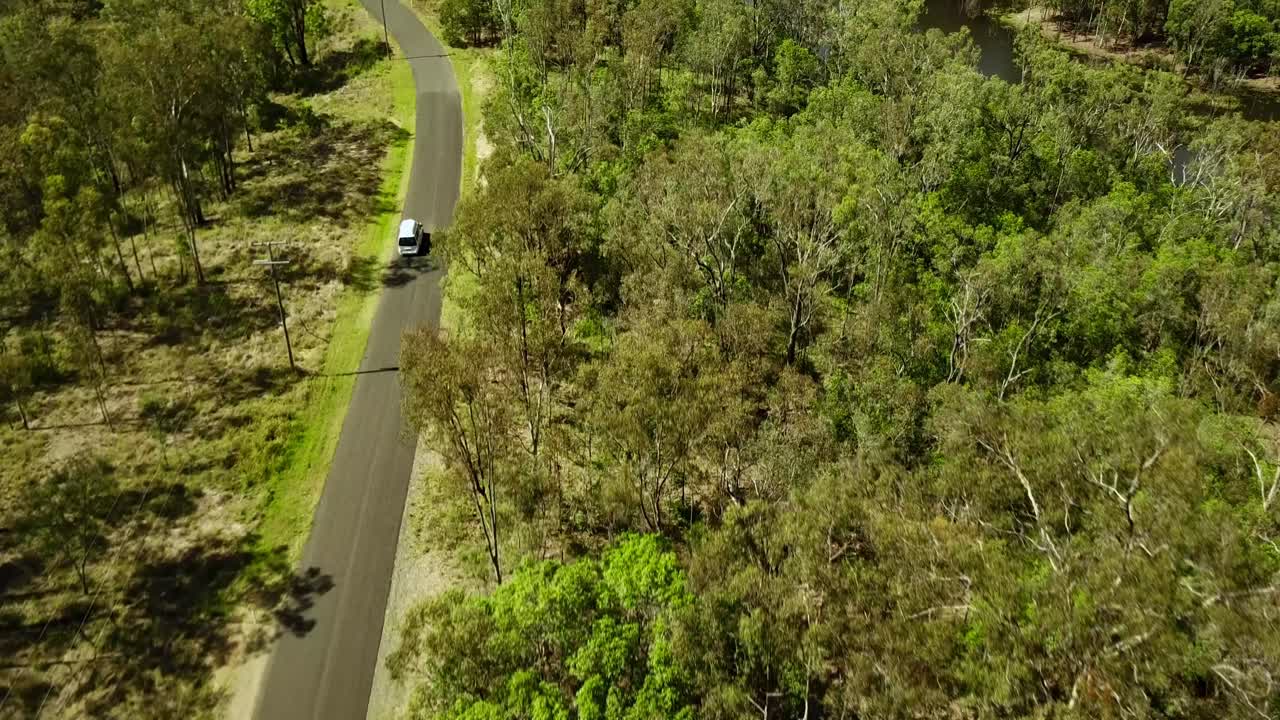vista aérea de una autocaravana en la carretera a través de arbustos verdes en australia