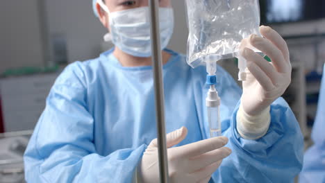 caucasian female surgeon applying drip in operating theatre, slow motion