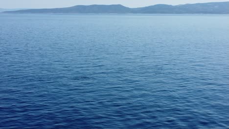 Un-Grupo-De-Delfines-Adriáticos-Filmados-Desde-El-Ascensor,-Con-La-Isla-De-Brac-En-Croacia-Al-Fondo